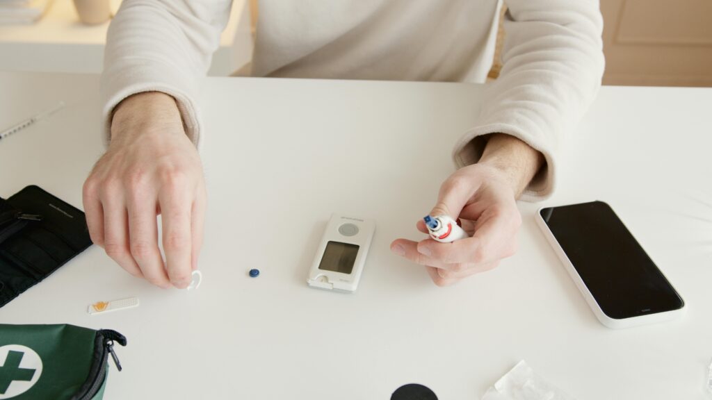 Person using glucometer and kit to check blood glucose levels.